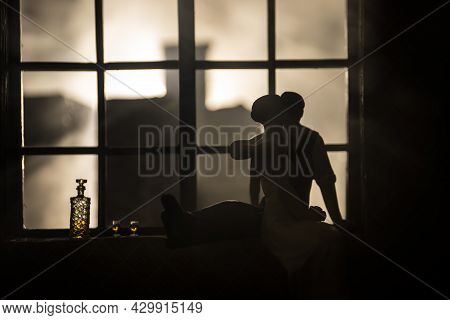 A Realistic Dollhouse Living Room With Furniture And Window At Night. Romantic Couple Sitting On Win