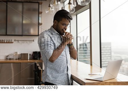 Pensive African Guy Looks At Laptop Pondering Over Problem Solution