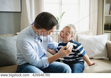 Father With Happy Down Syndrome Son Indoors At Home, Talking.