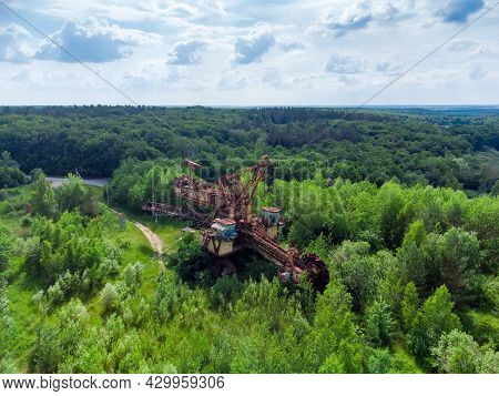 Large Old Abandoned Bucket Wheel Excavator Among The Trees Close To Quarry, Aerial View