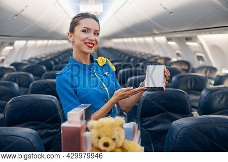 Pretty Stewardess In Bright Blue Uniform Smiling At Camera, Advertising Perfume As A Gift While Lead