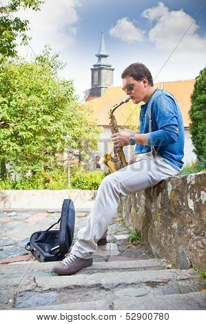 Young saxophonist plays on her sax with bright emotions in the street. Serbia.
