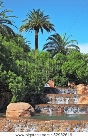 The spectacular cascade fountain. Multistage stone fountain surrounded by tropical vegetation and palm trees