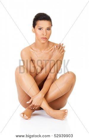 Beautiful and naked women sitting and covering her nudity by her legs and arms. Front view. . Isolated on white.