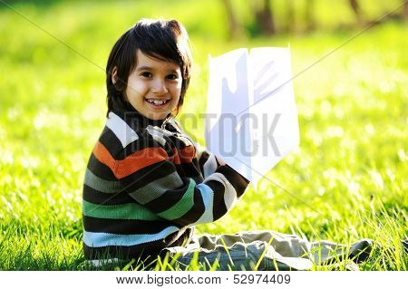Happy kid enjoying sunny late summer and autumn day in nature on green grass