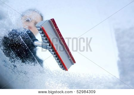 winter driving - scraping ice from a windshield