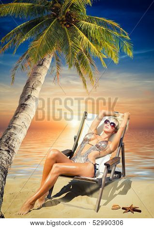 Beautiful young woman in bikini on the beach onder a coconut tree 