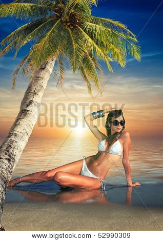 Beautiful young woman in bikini on the beach onder a coconut tree 