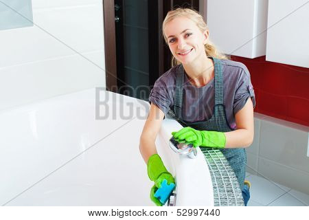 Woman cleaning bath at home. Female washing bath