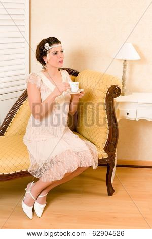 Attractive vintage 1920s woman sitting on a chaise longue