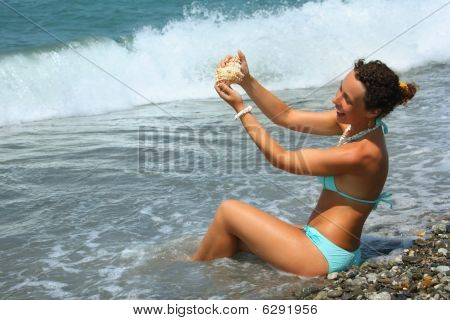Smuk kvinde vasker Seashell i havet
