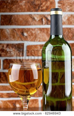 Wine bottle and glass on brick wall background