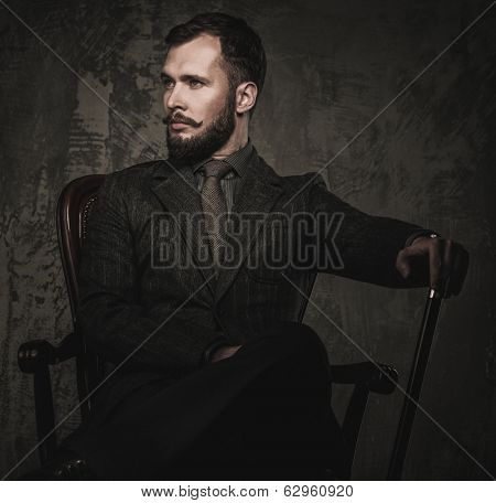 Handsome well-dressed with stick sitting in leather chair 