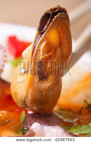 Mussel Hold Chopsticks Macro Against A Plate With Seafood.