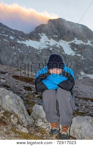 Young Girl Sitting On A Rock With Mountain View