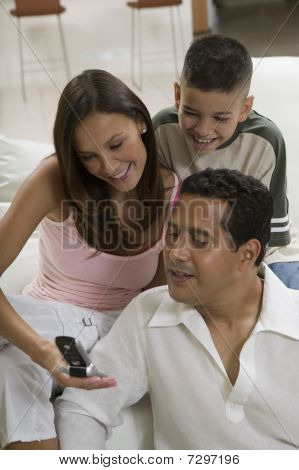 Familie zittend op de bank kijken naar foto op mobiele telefoon