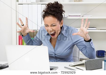Angry woman with computer at workplace - bad message.