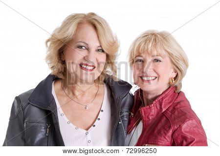 Two Caucasian older women in pension smiling at the camera. 