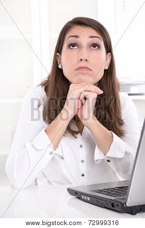 Bored businesswoman at desk looking up from laptop