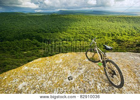 bicycle on a cliff with covered by forest hills