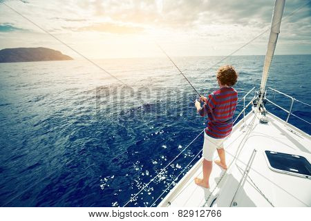 Young man fishing in the sea from sail boat