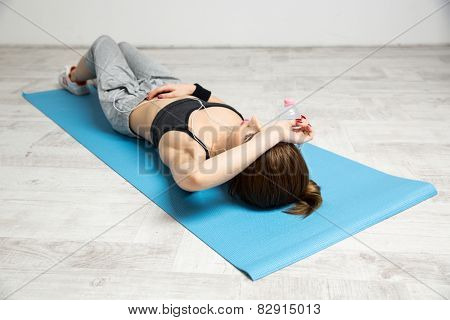 Beautiful woman lying on the yoga mat at gym