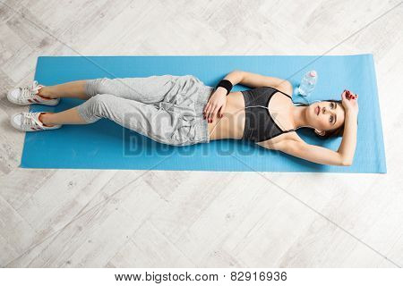 Top view portrait of a young woman lying on the yoga mat at gym