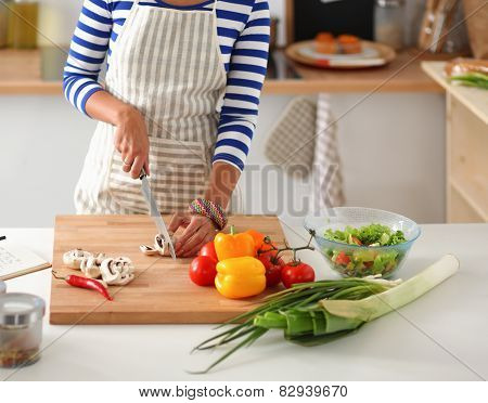 Young woman cutting vegetables in kitchen