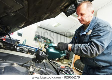 auto mechanic technician replacing and pouring motor oil into automobile engine at maintenance repair service station