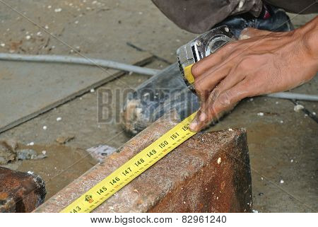Workers using measuring tape to measure mild steel