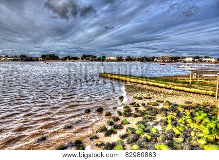 Christchurch harbour near Mudeford Dorset England UK with rocks green seaweed boats and cloudscape