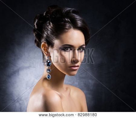 Young, beautiful and rich woman in jewels of platinum and stones over luxury background 