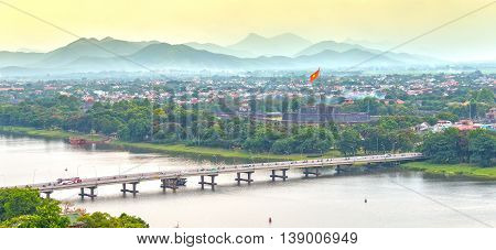 Hue, Vietnam - June 21st, 2015: Bridge connects both sides Perfume River beautiful, distant flag flying in port Hue Citadel, horizon Ngu Binh Mountain scenery makes this place very poetic, idyllic