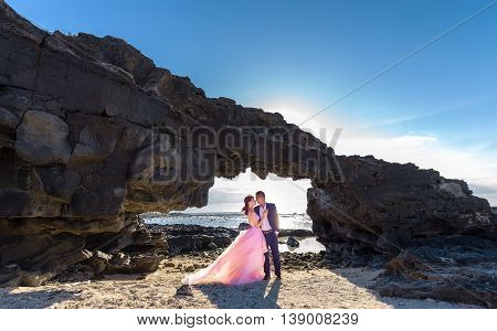 Ly Son Island, Vietnam, June 27th, 2015: Couple happy with stone gate on bay when the afternoon sun gradually to create a halo behind highlighters enjoying holiday island wilderness