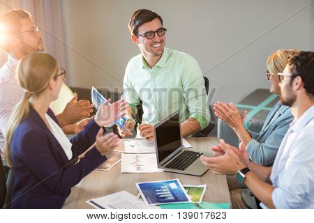 Coworkers applauding a colleague after presentation in the office
