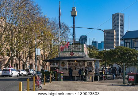 Sydney Australia - Jul 03 2016: Harry's Cafe de Wheels is an iconic pie cart on Cowper Wharf Road with cityscape on the background. They are best known for their meat pie "Tiger Pie". Woolloomooloo