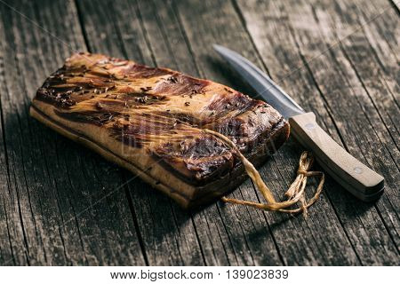 Fresh smooked bacon on old wooden table.