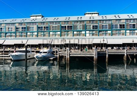 Finger wharf restaurants and hotel in Woolloomooloo bay with unrecognisable people in the distance. Sydney Australia