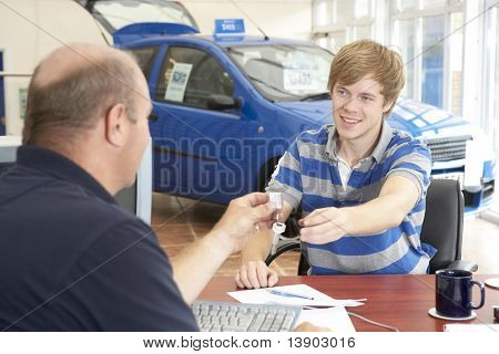 junger Mann schreibarbeit in Autosalon ausfüllen