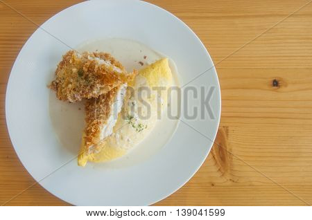 Flat lay of Omurice / Omelette rice with fish fried / Fried rice wrapped in egg Japanese food on wooden table