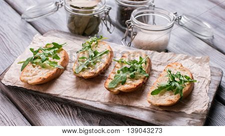 Pieces of grilled baguette. Bread and arugula leaves. Preparation of simple snack. Fresh and crispy appetizer.