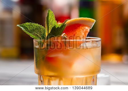 Orange beverage in a glass. Ice and leaves of mint. Delicious homemede cocktail with grapefruit. Easy recipe of summer drink.