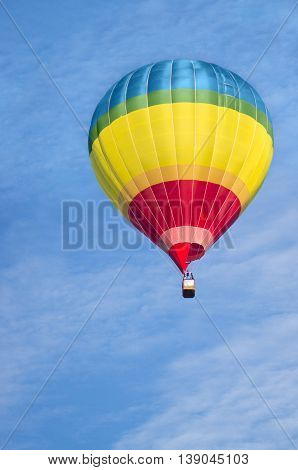 A colorful air balloon is floating in the blue sky.