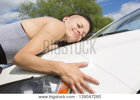A Cheerful young female driver hugging her new car