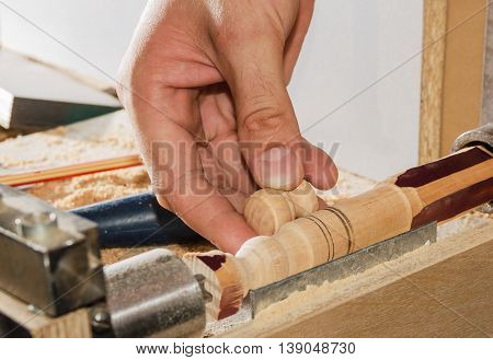 Carpenter working on the machine grind out piece of furniture