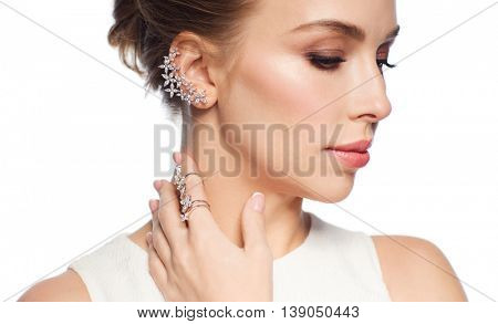 luxury, wedding and people concept - smiling woman in white dress with diamond jewelry over white background (focus on earring ang ring on finger)