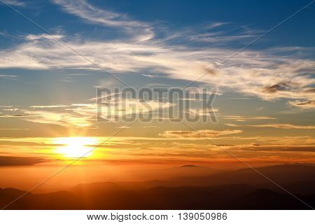 Magnificent sunset sky over silhouettes of the mountains