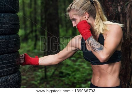Portrait of girl boxer doing uppercut kick working out outdoors