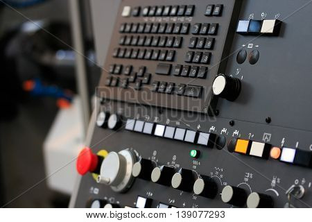 Modern CNC machining center with control panel on foreground. Close up view. Selective focus.