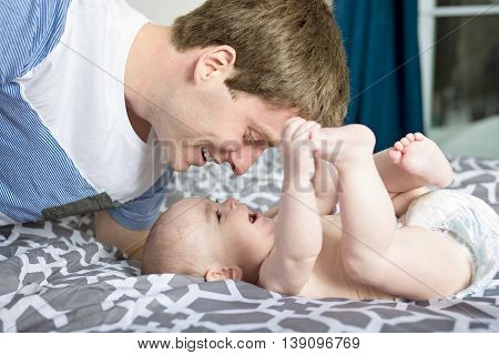 A Portrait of happy young father with a baby in the bed at home